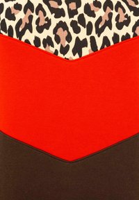 Kolorowy materiał tekstylny z nadrukiem geparda na górze, z czerwoną bandą poniżej i ciemnobrązowym sekcją na dole, wszystko w wzór chevron.