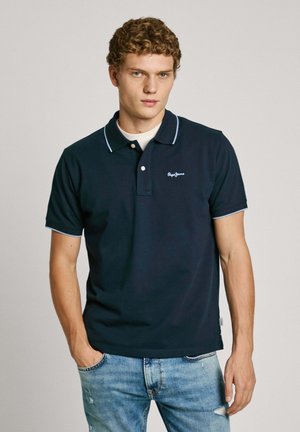 Marineblauwe polo met een drieknops sluiting en lichtblauwe accenten op de kraag en mouwen. Geborduurd logo op de linkerborst.
