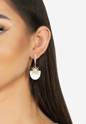 Gold-tone earrings featuring a starburst design with a white semi-circular accent and crystal detailing on the hook.