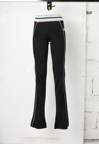 Μαύρο εφαρμοστό παντελόνι με λευκές ρίγες στο πλάι και πολύχρωμη ριγέ ζώνη, παρουσιασμένο σε ομοίωμα μπροστά σε λευκό τοίχο.