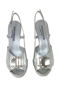 Decolté slingback aperti in argento con fascia metallica lucida, materiale in pelle, texture liscia e marchio sulla soletta.