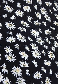 Tissu noir présentant un motif floral répété de marguerites blanches avec des centres jaunes, créant un design texturé et vibrant.