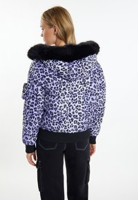 Giacca imbottita a stampa leopardata viola con cappuccio in finta pelliccia nera e polsini a coste, dotata di dettagli con tasche laterali a zip e cuciture a contrasto.