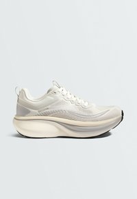 Baskets blanches de sport avec semelle épaisse coussinée, empeigne en maille, lacets et languettes à l'arrière et sur la languette.