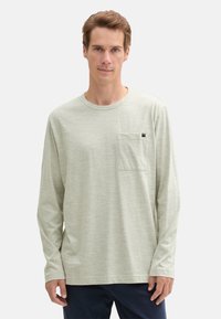 Langärmliges, hellgrünes T-Shirt aus weichem Stoff, mit in der Brusttasche und rundem Halsausschnitt. Minimale Textur und keine Muster.