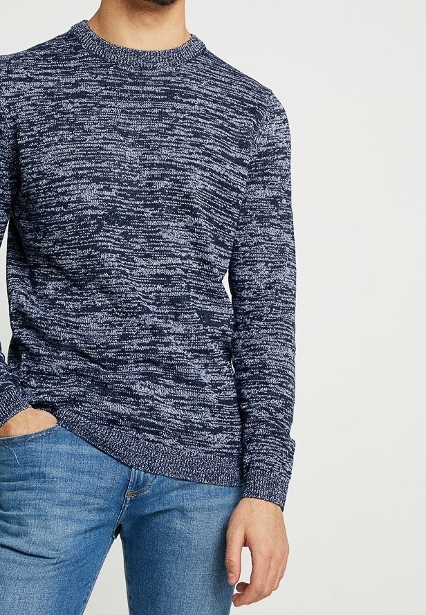 Maglione a collo rotondo di colore blu navy realizzato in maglia con motivo testurizzato e melange. Presenta polsini aderenti ed è abbinato a jeans blu chiaro.