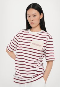 Hvid t-shirt med burgundy horisontale striber, rund halsudskæring og korte ærmer. Har en firkantet lomme med trykt tekst. Blødt bomuldsstof.