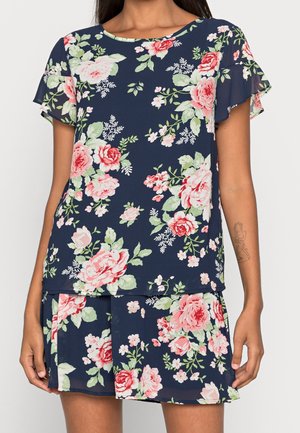 Navy blue short-sleeve top and skirt set with pink and white floral pattern worn by person with arm tattoo.