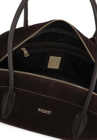 Borsa a tracolla in suede marrone con manici in pelle, accessori in oro e chiusura con zip. Presenta un interno in tessuto nero con una piccola tasca con zip.