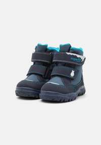Botas infantiles en azul marino y verde azulado con dos correas de velcro, cuello acolchado, suela de goma y detalles de costura en azul claro. Diseño cómodo.