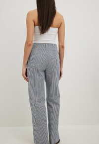 Wide-leg trousers in navy and white vertical stripes, featuring a high waist, smooth texture, and two back pockets.