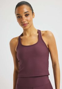Camiseta atlética de canalé burdeos con escote redondeado y tirantes anchos, diseñada para la comodidad y el movimiento. Textura suave en toda la prenda.