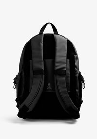 Mochila negra hecha de material suave, con correas de hombro acolchadas, un respaldo de malla y un logo de calavera en el bolsillo frontal.