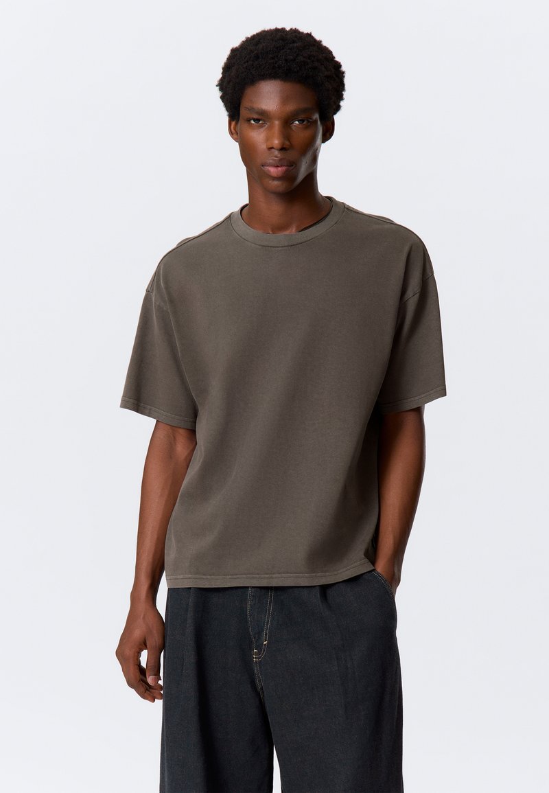 Olijfgroene oversized katoenen T-shirt met een ronde hals en korte mouwen, met een relaxte pasvorm en minimalistisch ontwerp.