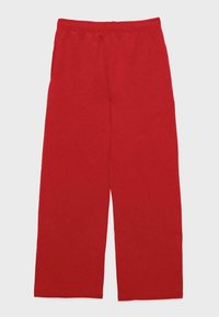 Rdeče elastične hlače z ravnimi nogami in casual slogom, položene na ravno površino na belem ozadju.