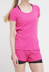 Rosa sportsoverdel och shorts med texturerad yta, rund halsringning och korta ärmar, med en diskret logodetalj på bröstet.