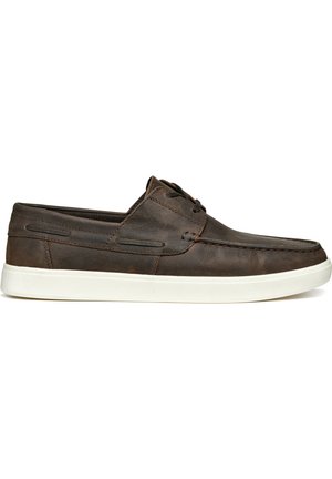 Bateaux en cuir marron avec une semelle en caoutchouc blanc, présentant un détail de couture subtil et un système de laçage, offrant un design décontracté.