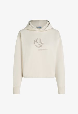 Kreminė gobtuvė su raišteliu, su kontrastingu "KL" logotipu ir liniuotės akcentais priekyje. Minkšta medžiaga ir trumpinta konstrukcija.