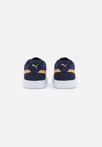 Baskets en suede bleu marine avec semelles en caoutchouc blanc, dotées d'une bande orange contrastante et d'accents de logo doré sur le talon.