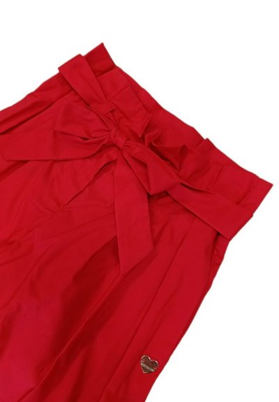 Rote Stoffshorts mit einem breiten Bund und einer Schleifendetail vorne. Mit einem kleinen metallischen Herzakzent an der Seite.