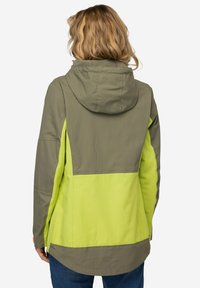 Chaqueta con capucha que presenta una sección superior en verde oliva y una sección inferior en verde limón brillante, fabricada con un tejido ligero y texturizado.