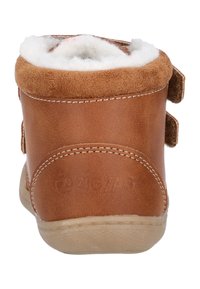 Bottine en cuir marron avec une doublure douce en fourrure blanche, équipée de bandes Velcro sur les côtés et d'une semelle en caoutchouc texturée.