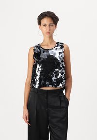 Fekete és ezüst flitteres crop top kerek nyakkivágással. Magas derekú fekete szatén nadrággal párosítva. Simaság, fényes megjelenés.