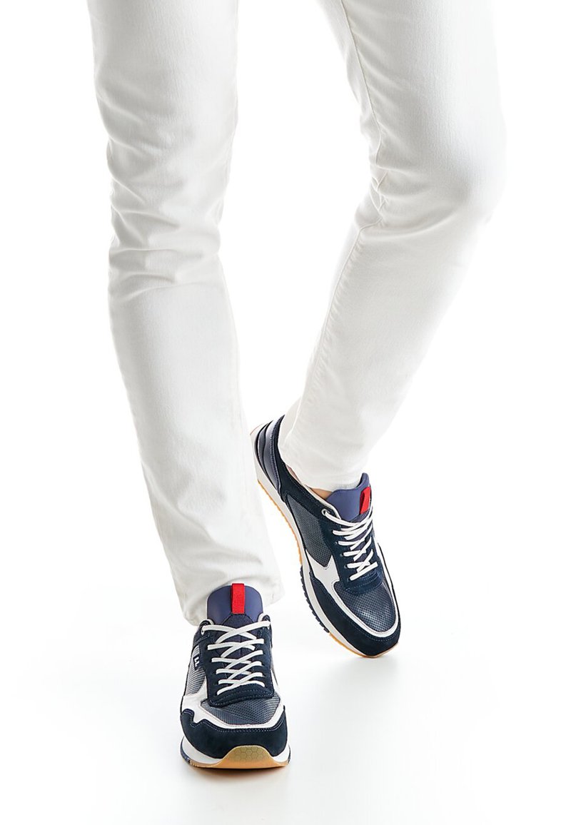 Marineblaue Laufschuhe aus Mesh- und Wildledermaterial; weiße Akzente; rote und blaue Details; Gummisohle; Schnürsenkel und gepolstered Zunge.