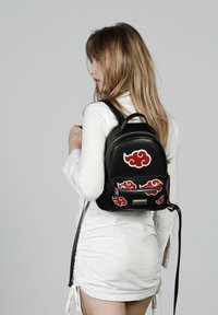 Sac à dos en cuir noir avec des motifs de nuages rouges, de forme arrondie, avec une poche zippée à l'avant et des bretelles réglables.