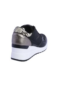 Zapatilla negra con parte superior acolchada, acentos en plateado metálico y un talón con estampado de serpiente texturizado. Suela blanca gruesa con una suela exterior negra.