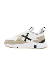 Sneaker bianco e beige con upper in rete, dettagli in camoscio, un logo nero prominente e un design della suola testurizzata. Presenta un tallone rinforzato.