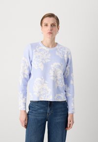 Lyseblå genser laget av mykt stoff, med et hvitt blomstermønster, rund hals og ribbede mansjetter og kant. Kombinert med mørke jeans.