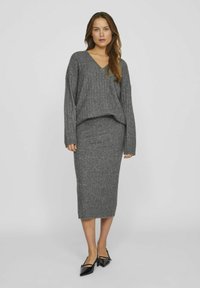 Suéter gris de punto con cuello en V y mangas largas, combinado con una falda midi a juego. El material parece suave con una textura acanalada.