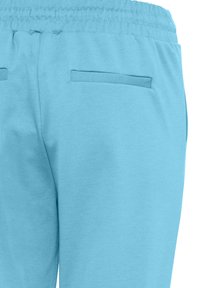 Lichtblauwe trainingsbroek met een elastische tailleband en twee achterste paspelzakken tegen een witte achtergrond.