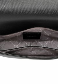 Zwarte tas met textuur en een slank ontwerp, voorzien van een zachte grijze voering en een logotag aan de binnenkant. Geopend zicht toont een ruime binnenkant.