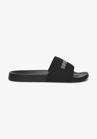 Zwarte slipper met een brede band met gouden "SUPERDRY" branding. Glad synthetisch materiaal en platte, gestructureerde zool.