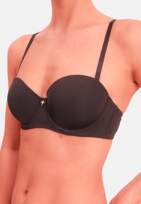 Sort polstret bh med justerbare stropper, der har en lille dekorativ charm i midten. Glat stof med syninger for struktur.