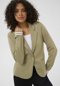 Olive green blazer with a tailored design, single button closure, and white striped cuffs. Smooth texture, fitted shape with side pockets.
