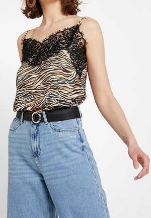 Camiseta sin mangas con estampado animal y borde de encaje negro, con tirantes finos. Combinada con unos vaqueros de tiro alto en azul claro y un cinturón negro con hebilla circular.