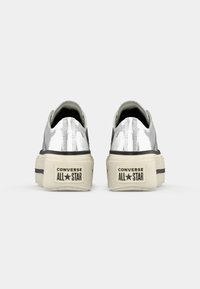 Strieborné metalické platformové tenisky Converse All Star s textúrovaným povrchom, čiernymi akcentmi a krémovou gumovou podrážkou s logom.