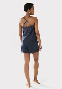 Navy satin sleep set featuring a lace-trimmed camisole with adjustable straps and matching shorts with scalloped edges and lace details.