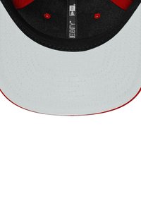 Baseballmütze mit einer weißen Front, schwarzem Schirm und roten Akzenten. Das Innere hat eine glatte Textur mit sichtbaren Nähten und einem Etikett.