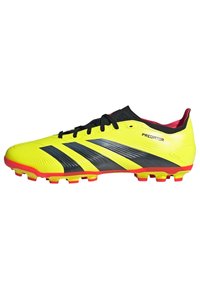 Botín de fútbol amarillo con rayas negras y acentos rojos, que presenta un diseño ligero y una parte superior texturizada para un mejor agarre.
