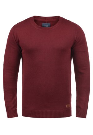 Burgundski pletene pulover s okroglo izrezom, dolgimi rokavi, rebrastimi manšeti in robom ter majhno blagovno znamko na spodnji strani.