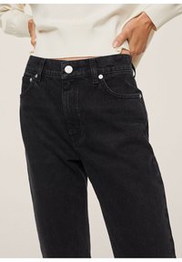 Jeans de denim negro con talle alto, botón plateado y bolsillos frontales. Presentan una textura suave y un diseño de pierna recta.
