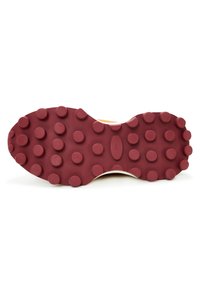 Semelle de chaussure avec une semelle extérieure en caoutchouc bordeaux présentant des motifs circulaires en relief uniformément répartis pour la traction et l'adhérence sur des surfaces planes.
