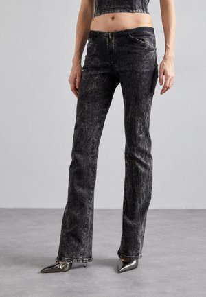 Mustad denim-stiilis laiad teksad, millel on kulumise mõju, esikott ja tõmblukk, koos terava metallist kontsaga kingadega.