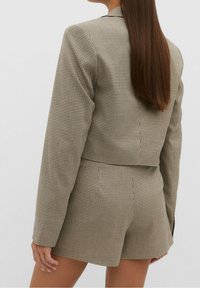 Brown and white checkered blazer with matching shorts. Tailored fit, textured fabric, long sleeves, single back vent, and pockets.