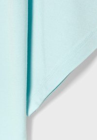 Tissu bleu clair avec couture visible et pli, montrant une texture douce et des détails de couture lisse sur un fond uni.