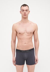 Graue Boxer Shorts aus weichem Stoff, mit einem schwarzen Bund, der den Text "JACK & JONES" trägt, und subtilen Stichdetails.